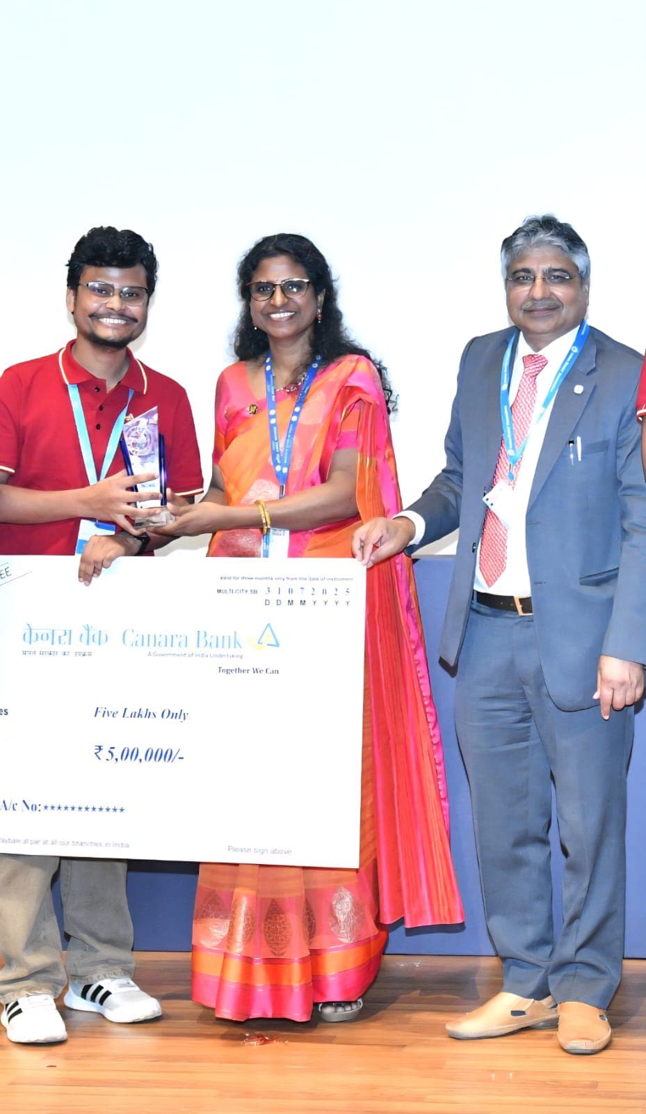 Receiving the ₹5,00,000 Canara Bank Cyber Suraksha Hackathon winners' cheque and trophy on stage.